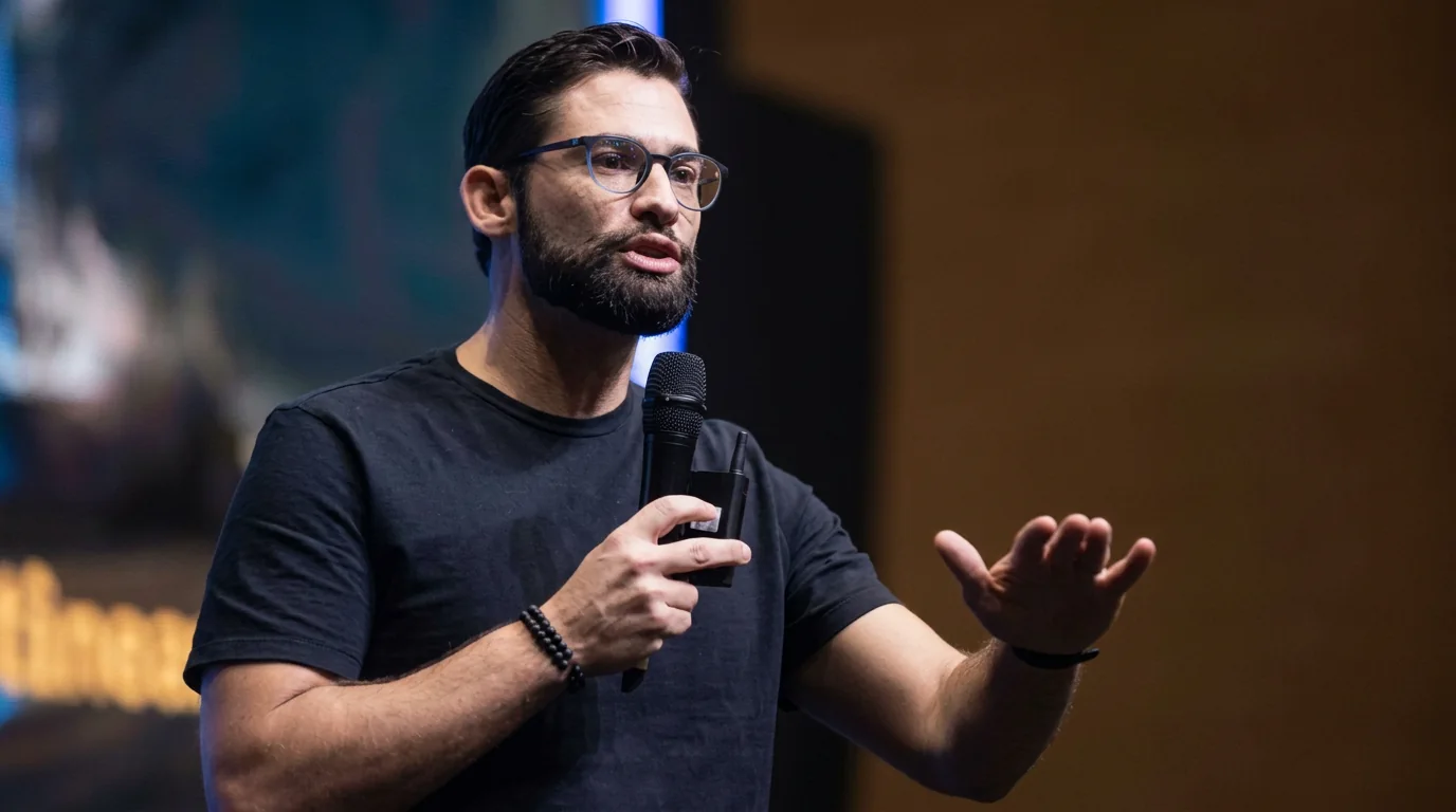 Piero Franceschi em palco, ao microfone, durante palestra sobre o trabalho de ser humano